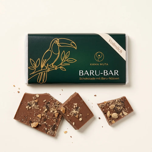 BARU-BAR Vollmilch, Schokolade mit Baru-Nüssen, Tafel in grüner Banderole mit Tukan auf cremefarbenem Hintergrund, davor drei Stücke Vollmilchschokolade mit gehackten Baru-Nüssen (KI-generiert)