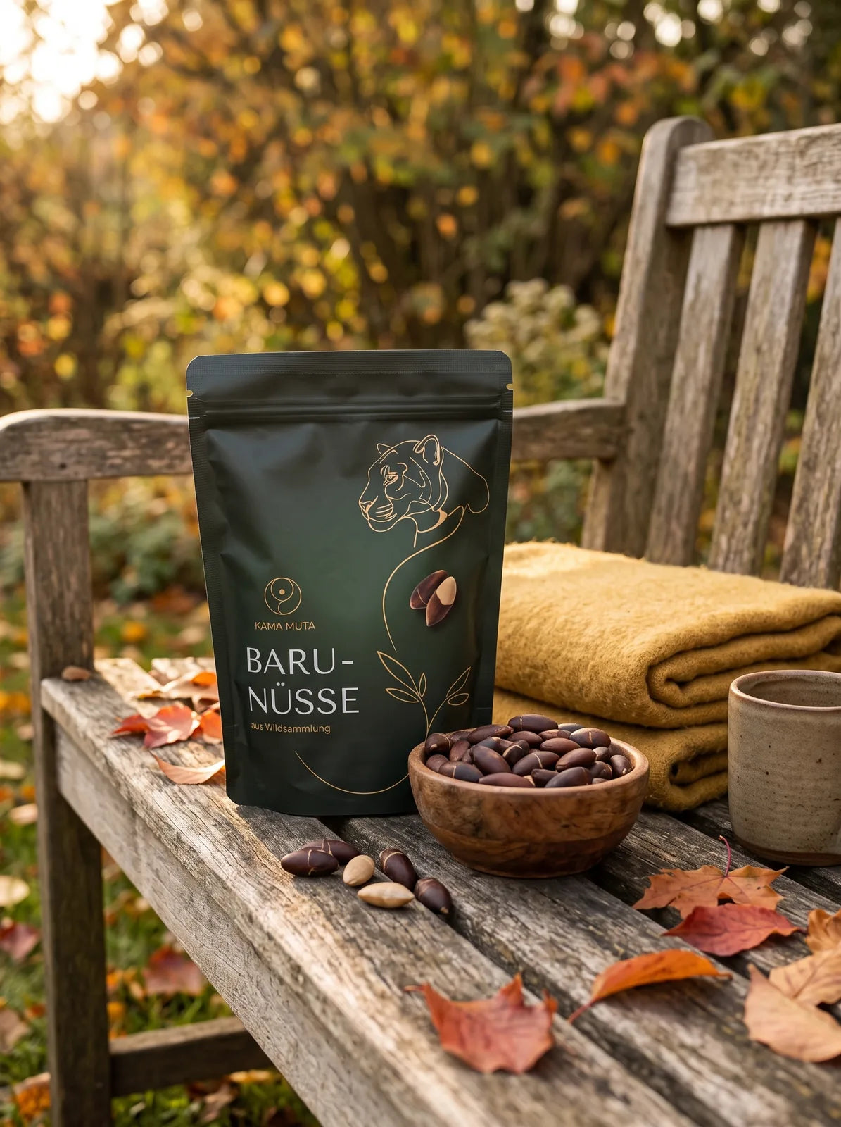 KAMA MUTA Baru-Nüsse 250 g auf einer alten Gartenbank im Herbst, daneben eine Holzschale mit Baru-Nüssen, eine senfgelbe Wolldecke und ein Becher (KI-generiert)