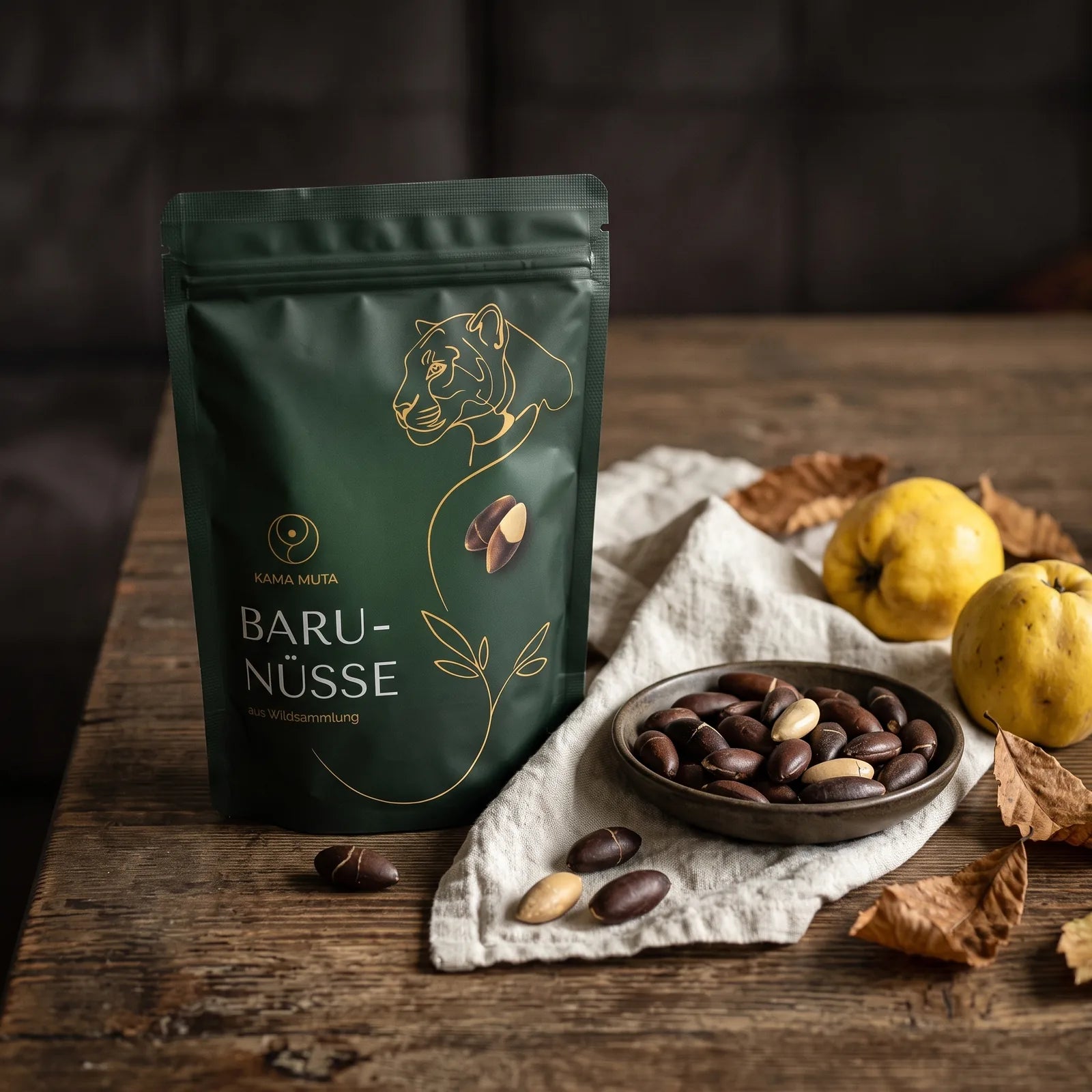 KAMA MUTA Baru-Nüsse 250 g auf einem dunklen Eichentisch mit Leinentuch, einer Schale gerösteter Baru-Nüsse, zwei Quitten und Herbstlaub (KI-generiert)